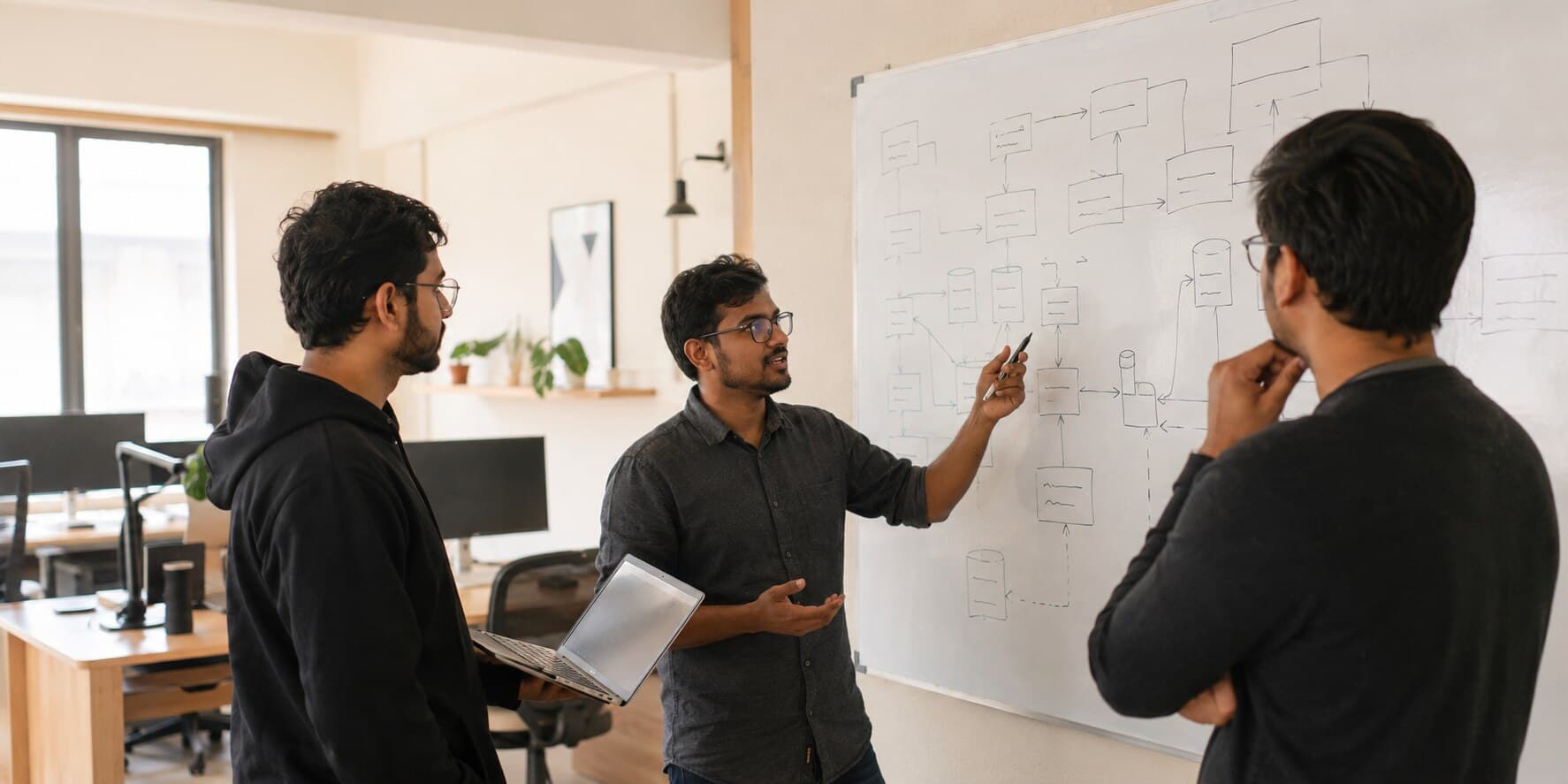 Three of the studio walking through a system's architecture at the whiteboard