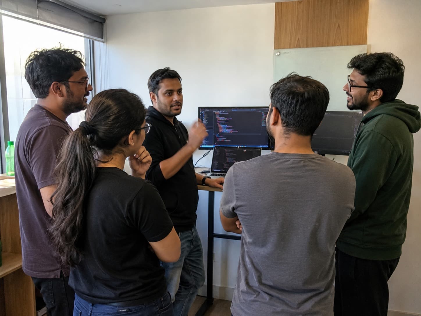 The team around a standing desk, mid-review of a pull request